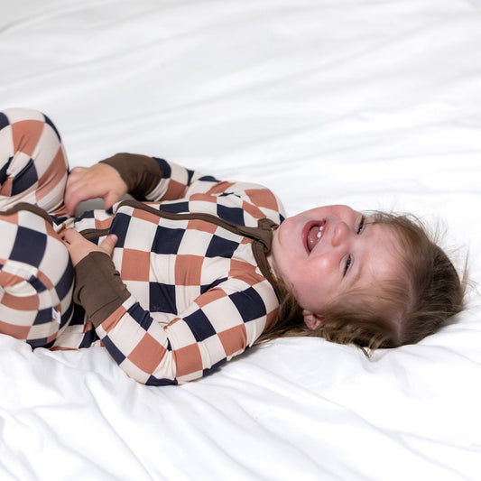 Baby lying on a white surface wearing a checkered outfit